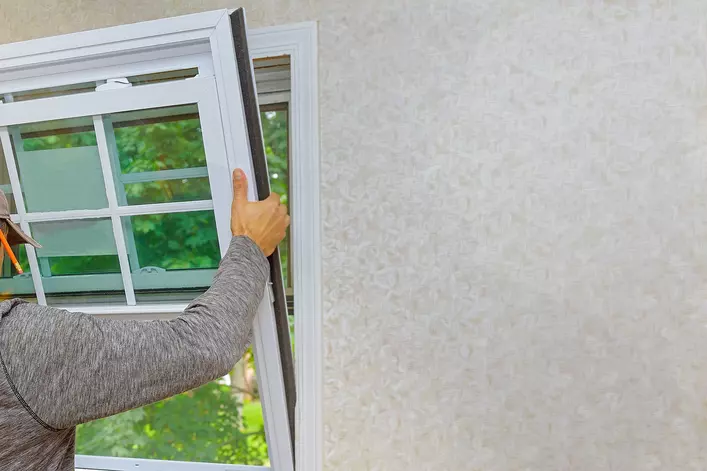 A contractor installing energy-efficient windows into a home to save thousands of dollars.