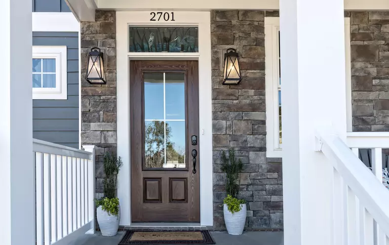 A 2 panel 3 quarter fiberglass entry door with a large glass for optimal visibility and natural light and a keypad lock for security on the front porch of a home.