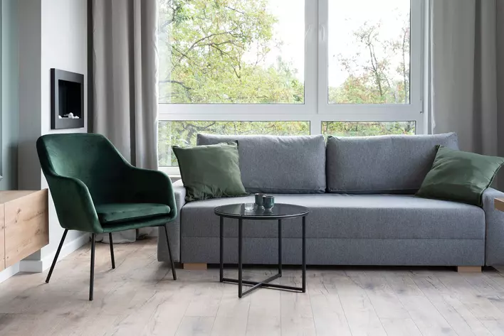 Furniture including a chair and a couch in front of a window.