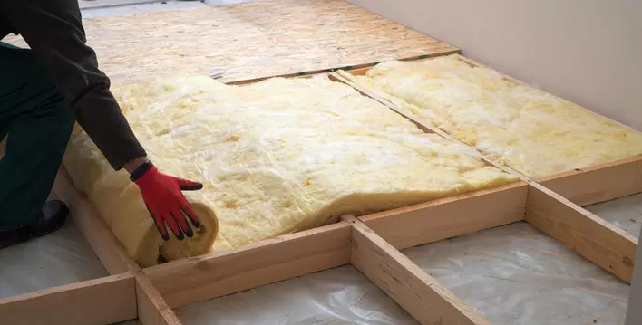 A person in the process of insulating the attic for an inexpensive solution to make the home more energy efficient.