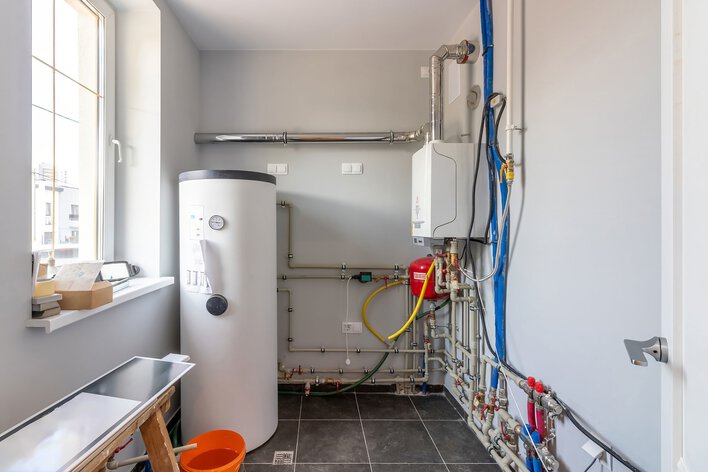 A room with a water heater and pipes.