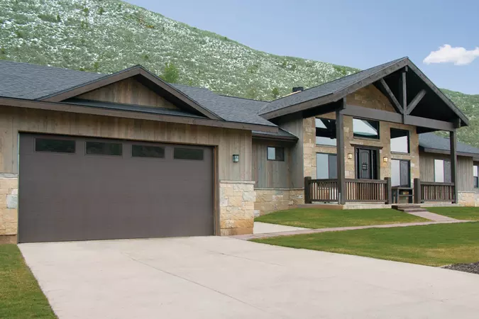 Black residential garage door with windows, installed in a suburban family home